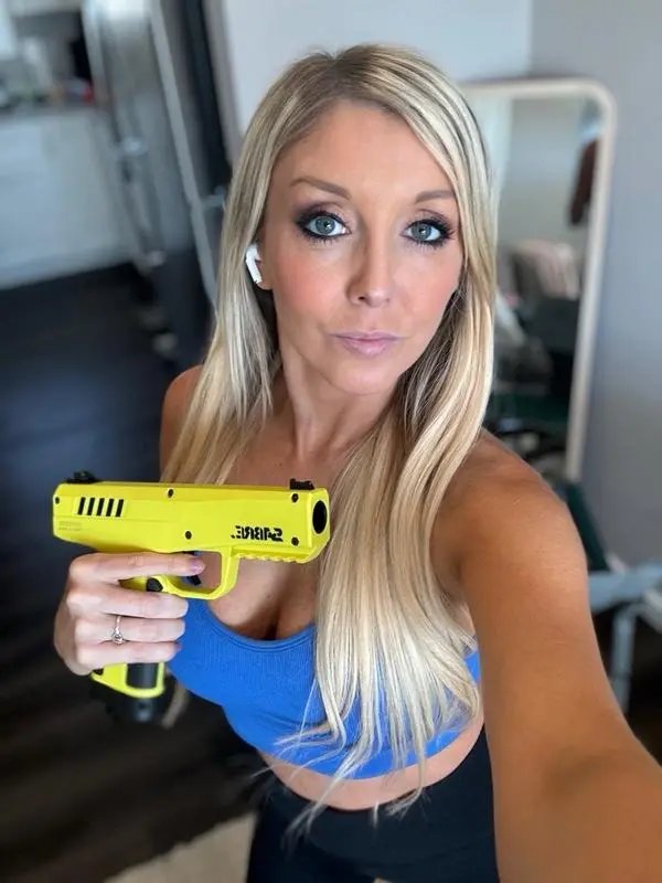 A woman holding a SABRE pepper projectile launcher