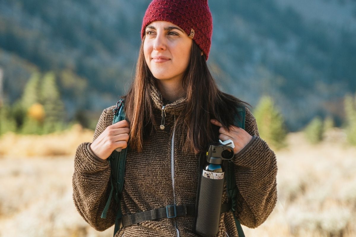 girl hiking while carrying bear spray